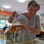 Ženska preliva rjavkasto tekočino iz merilnega vrča v steklenice.
