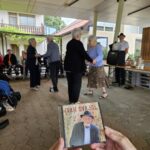 Roke držijo CD Ivana Švajgla, v ozadju stanovalci plešejo.