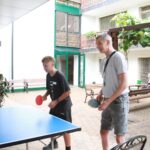 Dve osebi igrata namizni tenis na pokriti terasi.